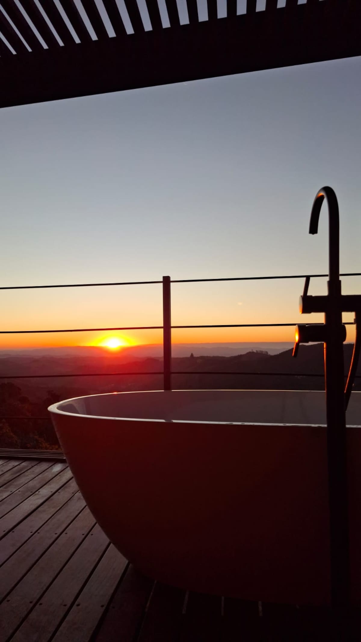 A banheira de imersão na varanda do chalé, de frente para o pôr do sol na serra