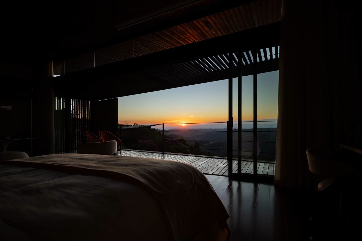 O pôr do sol visto da cama, atrás dos brises de madeira