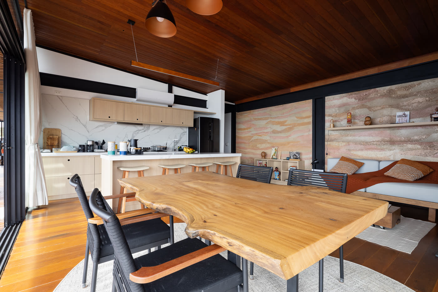 A mesa de jantar de madeira maciça com a cozinha ao fundo